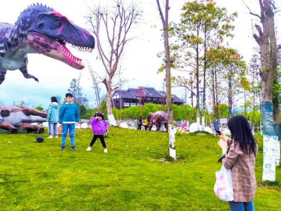 家长带着孩子在潼南大佛寺恐龙嘉年华露天科普乐园游玩。
