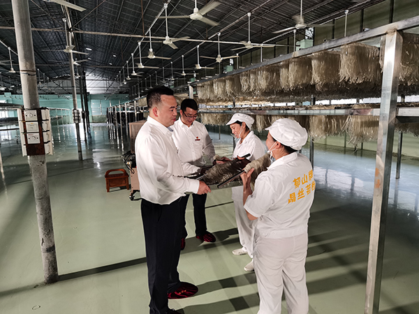 重庆农商行彭水支行客户经理在彭水县龙须晶丝苕粉有限公司实地查看生产经营情况，图为该公司生产车间一角。