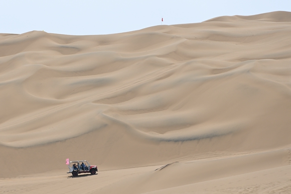 游客在新疆鄯善县库木塔格沙漠风景区乘坐沙漠冲浪车游览。