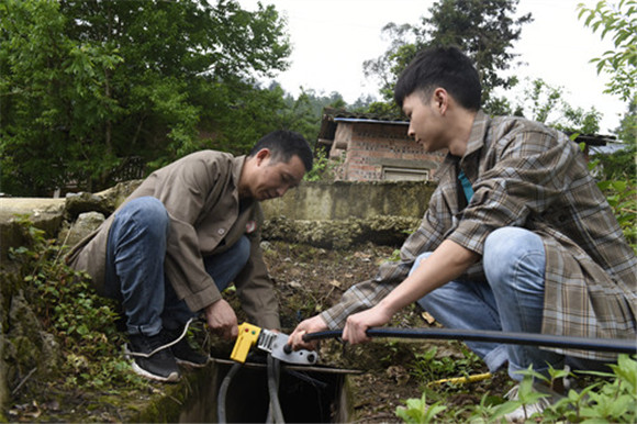 谭华权（左）与村干部在维修人饮水管 。特约通讯员 隆太良 摄