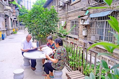 社区居民坐在新修的石凳上阅读报纸。通讯员 陈婷 摄