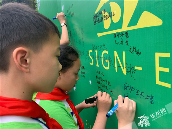 2、学生们在签名墙上写下环保寄语。华龙网-新重庆客户端记者 欧武夷 摄