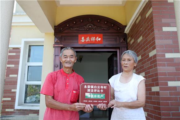 周维龙刘金容夫妇开心地展示“清洁卫生示范户”牌匾。通讯员 陈仕川 摄