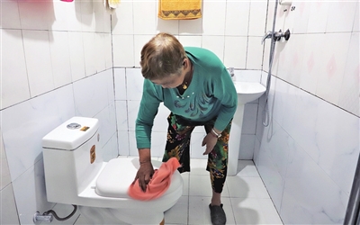 万婆婆正在打扫刚改造好的自家厕所。通讯员 江晓芸 摄