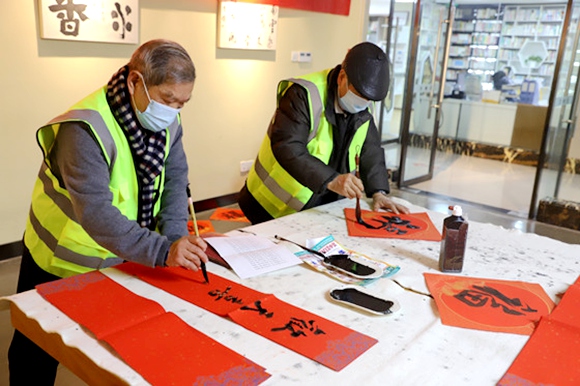 龙塔书画协会的文化志愿者们在街道文化中心综合楼书画室现场书写春联和福字。龙塔街道办事处供图 华龙网发