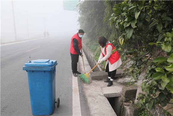 志愿者在道路沿线清扫垃圾。通讯员 陈刚 摄