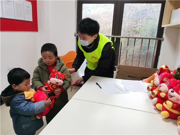 玉峰山村新时代文明实践志愿者为小朋友送“虎娃”。王家街道办事处供图 华龙网发