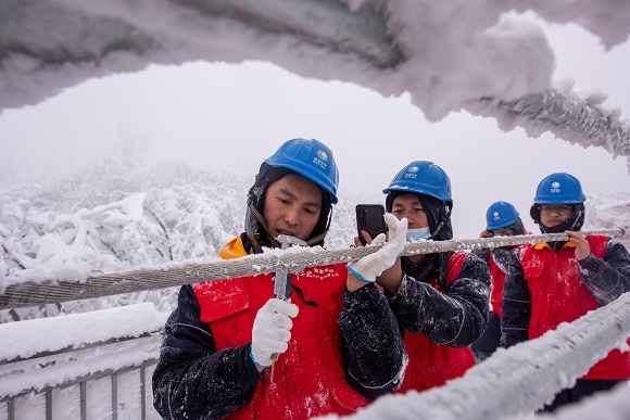 国网重庆城口供电公司员工在220千伏华城线237号塔测量覆冰厚度。通讯员 牟丹阳 摄