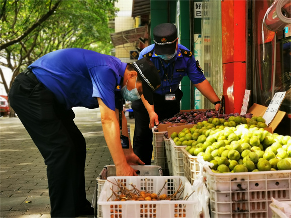 沙坪坝区城管执法队员协助商户规范摆放经营物品。沙坪坝区城市管理综合行政执法支队供图 华龙网发