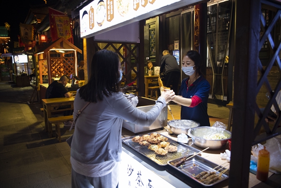 游客在太原古县城内购买小吃。