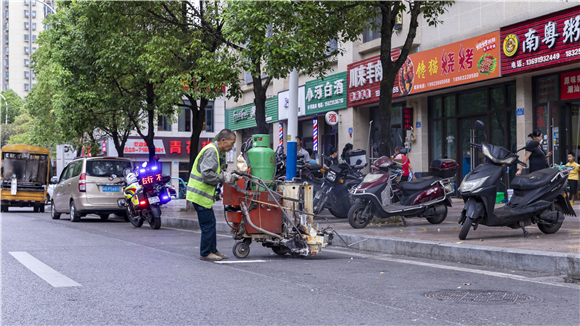工人正在路段两侧用热熔划线机施划限时停车位。重庆市停车管理事务中心供图 华龙网发