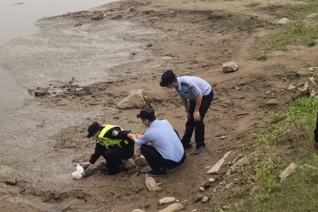 1民警清理白鹭周围的淤泥，帮它脱困。重庆市公安局水警总队供图