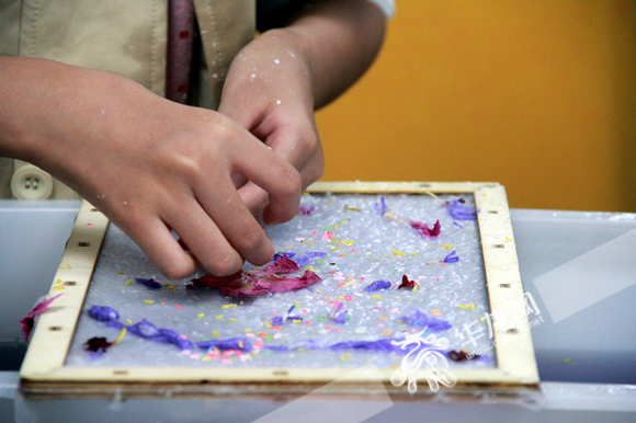一位小朋友正在为花草纸做造型装饰。华龙网-新重庆客户端 张颖绿荞 摄