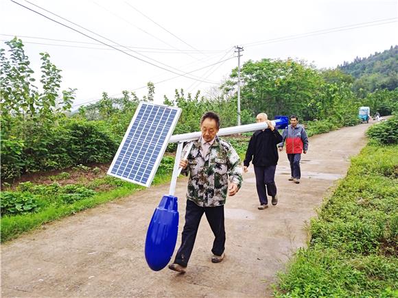 村民们将太阳能路灯搬运至安装点。通讯员 陈小红 摄