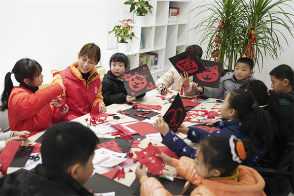 2022年1月，志愿者在重庆市北碚区未成年人救助保护中心指导孩子们制作迎春剪纸。市展览办供图