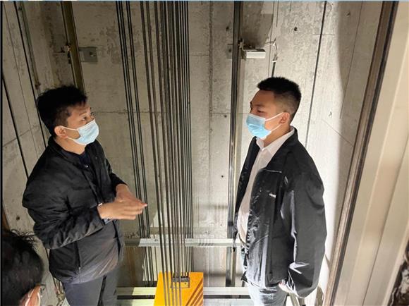 2工作人员与物业人员一起在协信城立方的电梯轿厢顶部进行检查。通讯员 周倩玉 摄