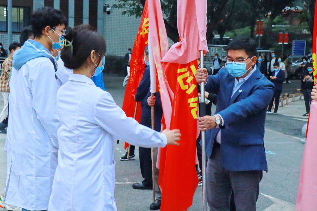 重庆医科大学校领导为志愿者授旗。受访单位供图