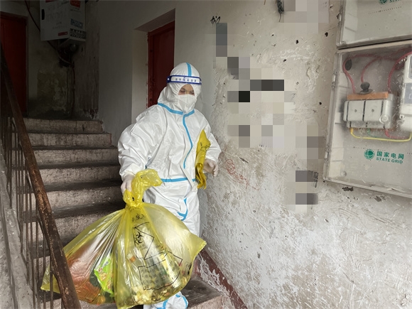 刘洋穿着防护穿梭在临时管控点为居民送菜清理垃圾。云阳县委组织部供图 华龙网发