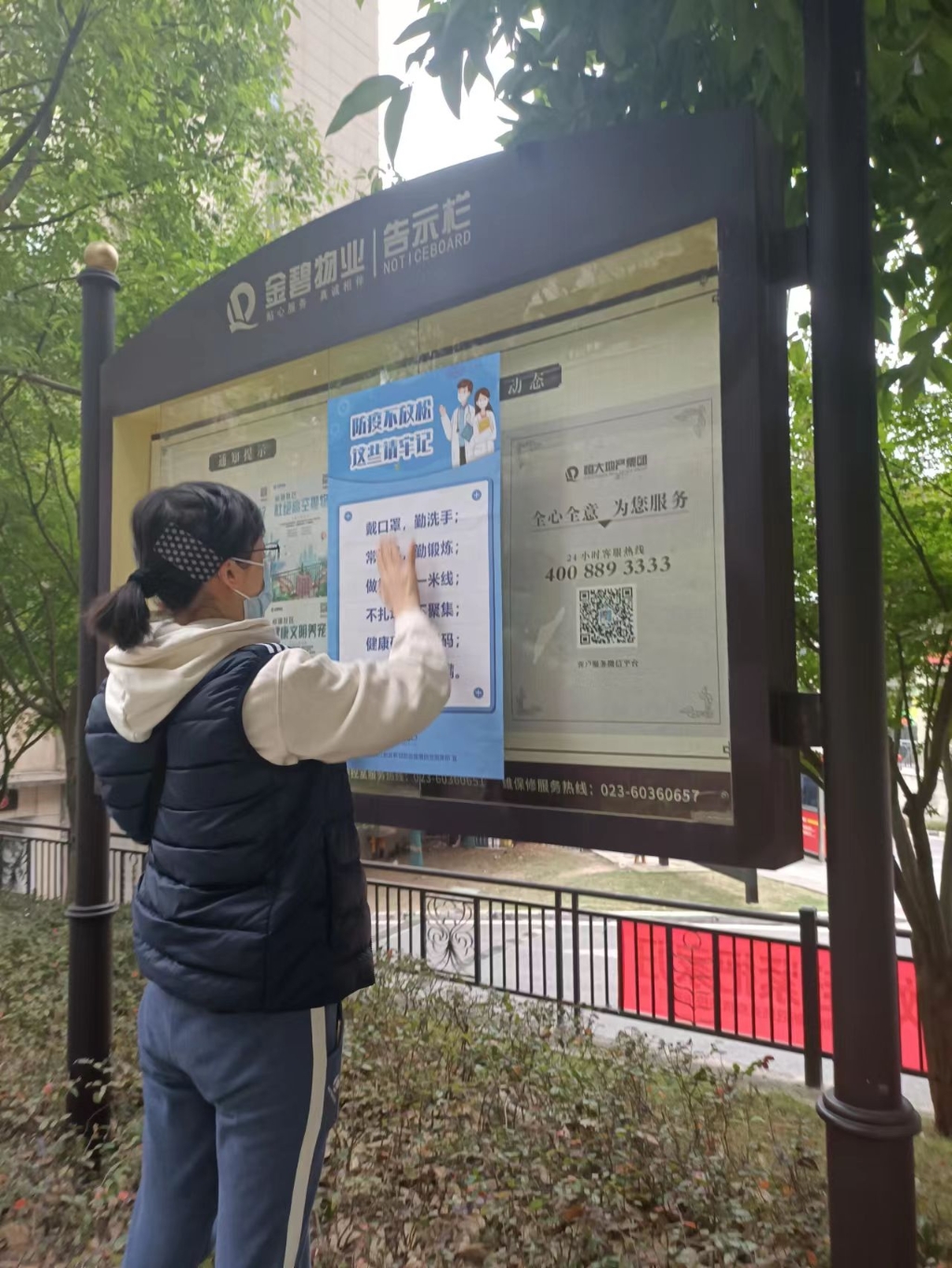 市大数据局机关信息化推进处党支部李小萍在社区张贴宣传海报。市大数据发展局供图