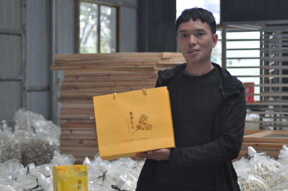何思勇展示设计其公司的菊花茶包装。通讯员 谭华祥 摄