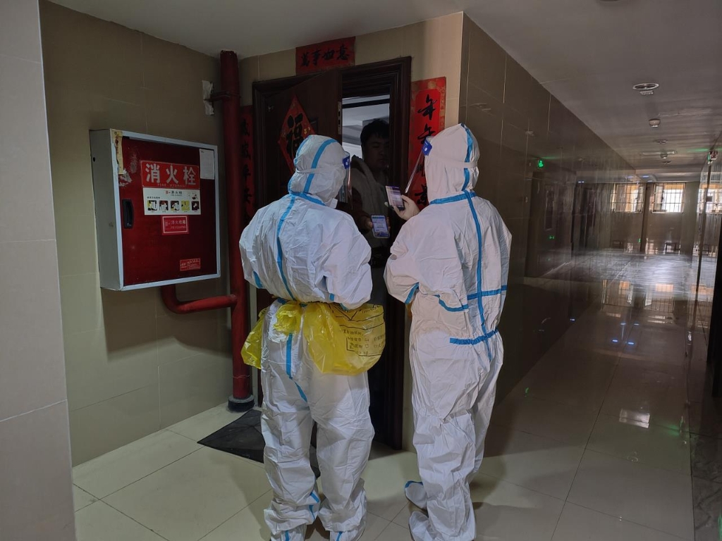 毛小华（右）协助医护人员上门采集核酸，开展扫码、登记等工作。受访者供图