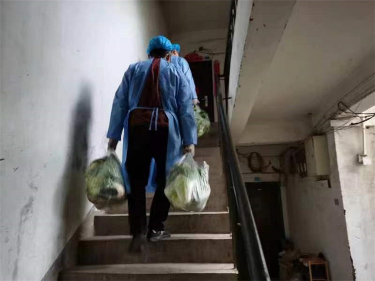 手提大包小包，志愿者爬楼梯送菜上门。王家街道办事处供图 华龙网发