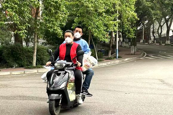 李成和夫妻骑着摩托为居民们送生活物资。聂晓珂 摄 