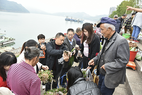 秦大益在帮菜农和买菜市民兑换现金。