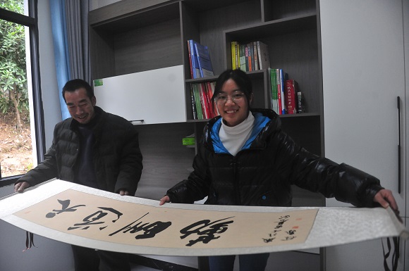 刘云斌和刘霜两父女俩在书房里展示市级书法家徐飞赠送的书法作品。通讯员 龚节品 摄