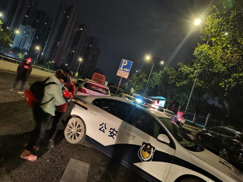 1李女士怀抱孩子上警车。重庆两江新区警方供图
