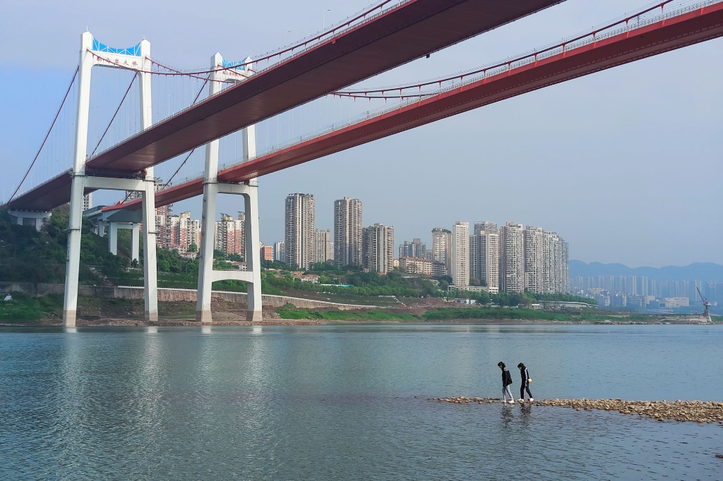 2022年3月23日，重庆市九龙坡区鹅公岩大桥下方的长江边，人们在江边休闲。