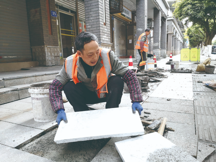 工人对化龙桥社区破损人行道进行整治。记者 袁启芳 摄