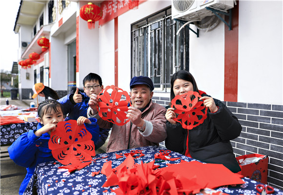 梁平区青少年活动中心师生和金带街道敬老院老人一起展示现剪的窗花作品。熊伟 摄