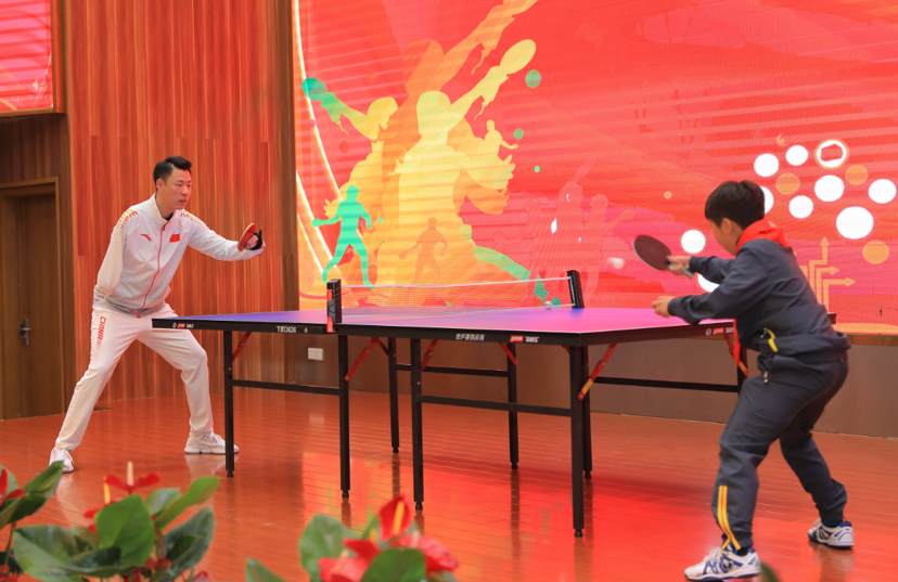 一场奥运冠军和小学生的乒乓球比拼正在精彩进行
