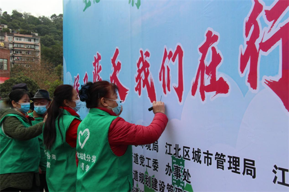 志愿者们在环保宣传主题展板上签名，表示将共同保护环境、保卫蓝天。郭家沱街道供图