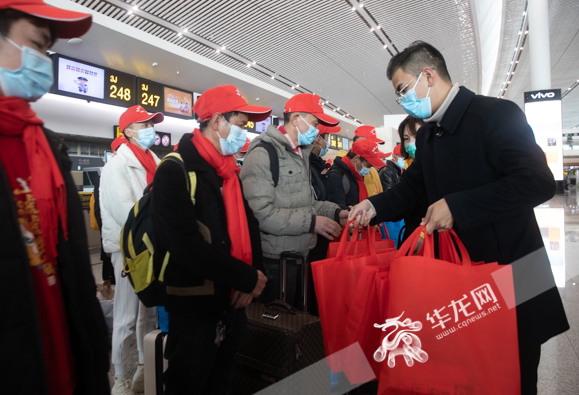 重庆市就业服务管理局组织的送行活动上，工作人员为即将前往山东的民工赠送礼包。华龙网-新重庆客户端记者 张质 摄