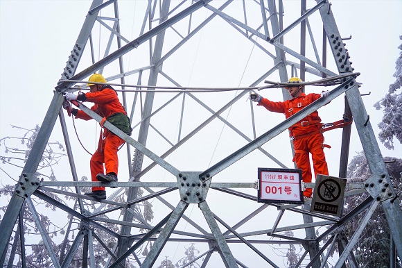 电力巡线工人对110千伏坝丰线1号铁塔覆冰进行测量。通讯员 罗一灵 摄