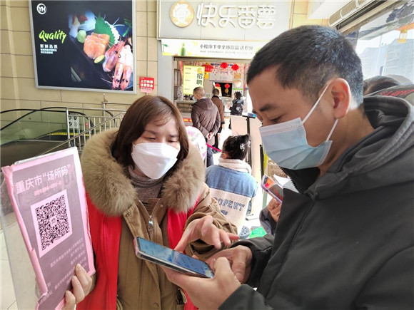志愿者在永辉超市门口提醒市民出示场所码进入商场。潼南区委宣传部供图   华龙网发