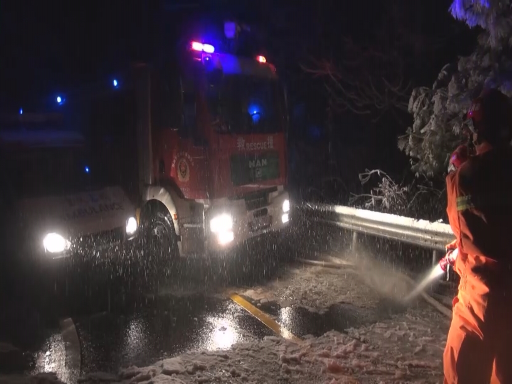 0消防员试图用水冲开积雪，让救护车前行。黔江消防供图 华龙网-新重庆客户端 发