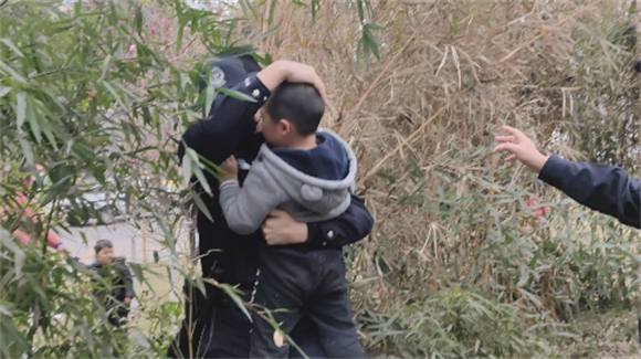 0民警从草丛深处的竹林下抱出男孩。沙坪坝区警方供图 华龙网-新重庆客户端 发