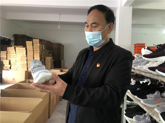 秀山县龙洞鞋业有限公司生产车间厂长李保卫正对产品进行质检。通讯员 杨帆 摄