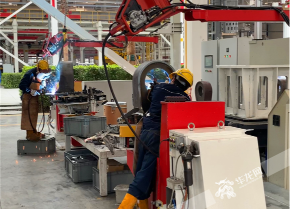 工人与机器人协作，正在进行焊接。华龙网-新重庆客户端记者 刘钊 摄