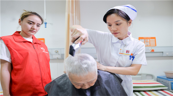 “生命花”志愿者帮老人理发。九龙坡区人民医院供图 华龙网发