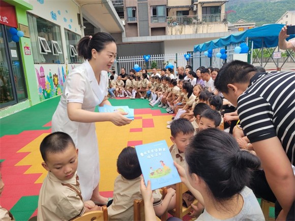 县妇联副主席为家长们发放《重庆市家庭教育指导读本》。巫溪县妇联供图 华龙网发