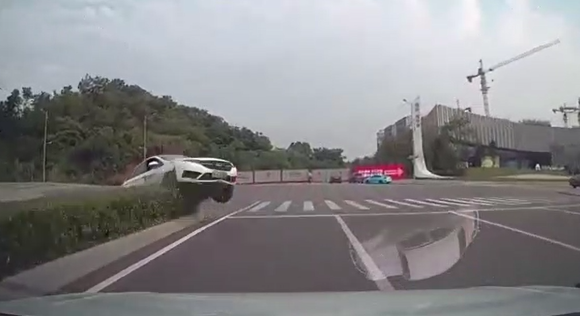 0网约车“飞”过绿化带撞向计先生白色轿车的瞬间。重庆高新区警方供图