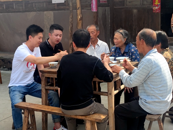 农家院子里，宝兴镇党委书记黄鑫与老乡们一边品乡宴一边攀谈。通讯员 廖海燕 摄