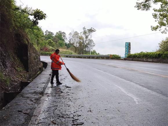 公路管养人谭其良正在清扫雨后路边的残渣。受访者供图
