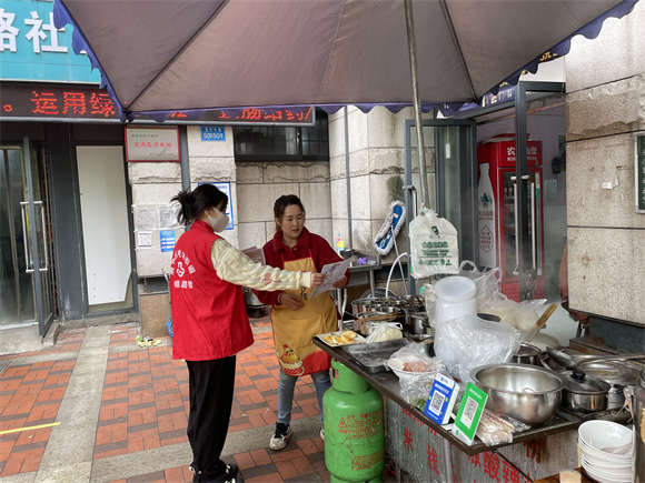 2龙山街道松牌路社区志愿者向商户宣传“文明餐桌”。通讯员 左春燕 摄