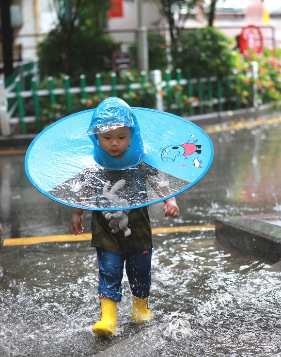 小孩子跑过积水路段。华龙网-新重庆客户端首席记者 李文科 摄