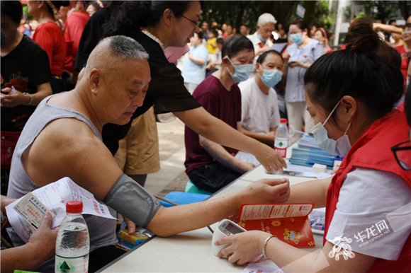 活动现场，志愿者为社区老人义务测量血压。华龙网-新重庆客户端 简梦 摄